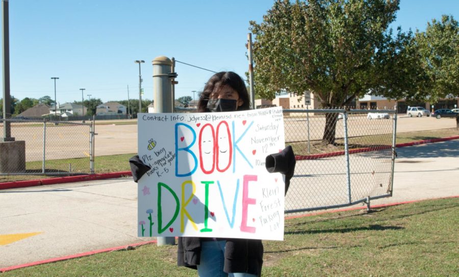 Senior Catherine Valverde held up a book drive sign by the street for advertisement.
