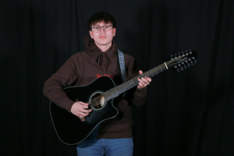 Junior Andy Soto poses with his guitar, a 12-string Takamine acoustic. 