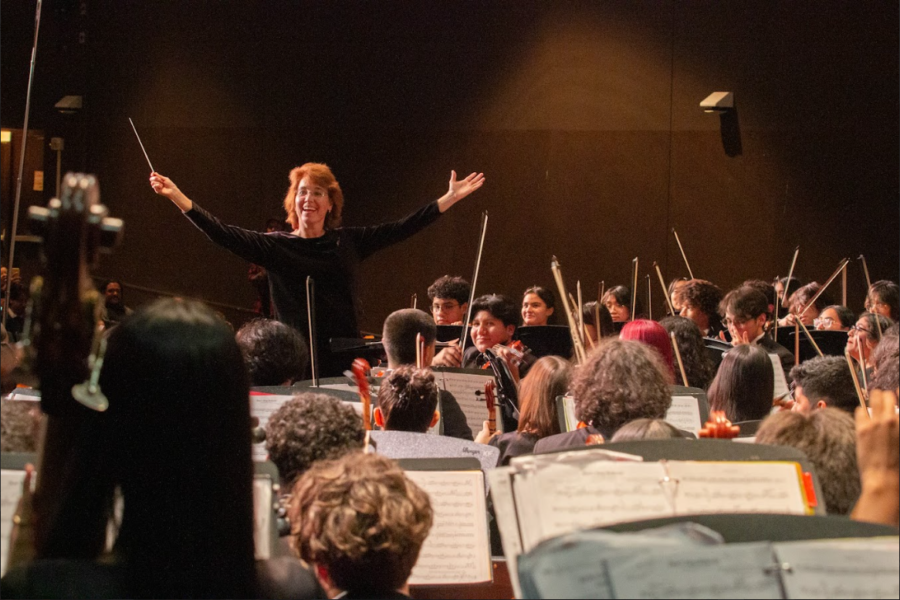 At the end of the last song with the all-combined orchestra, Mamie Morlacci throws her hands up and smiles. 